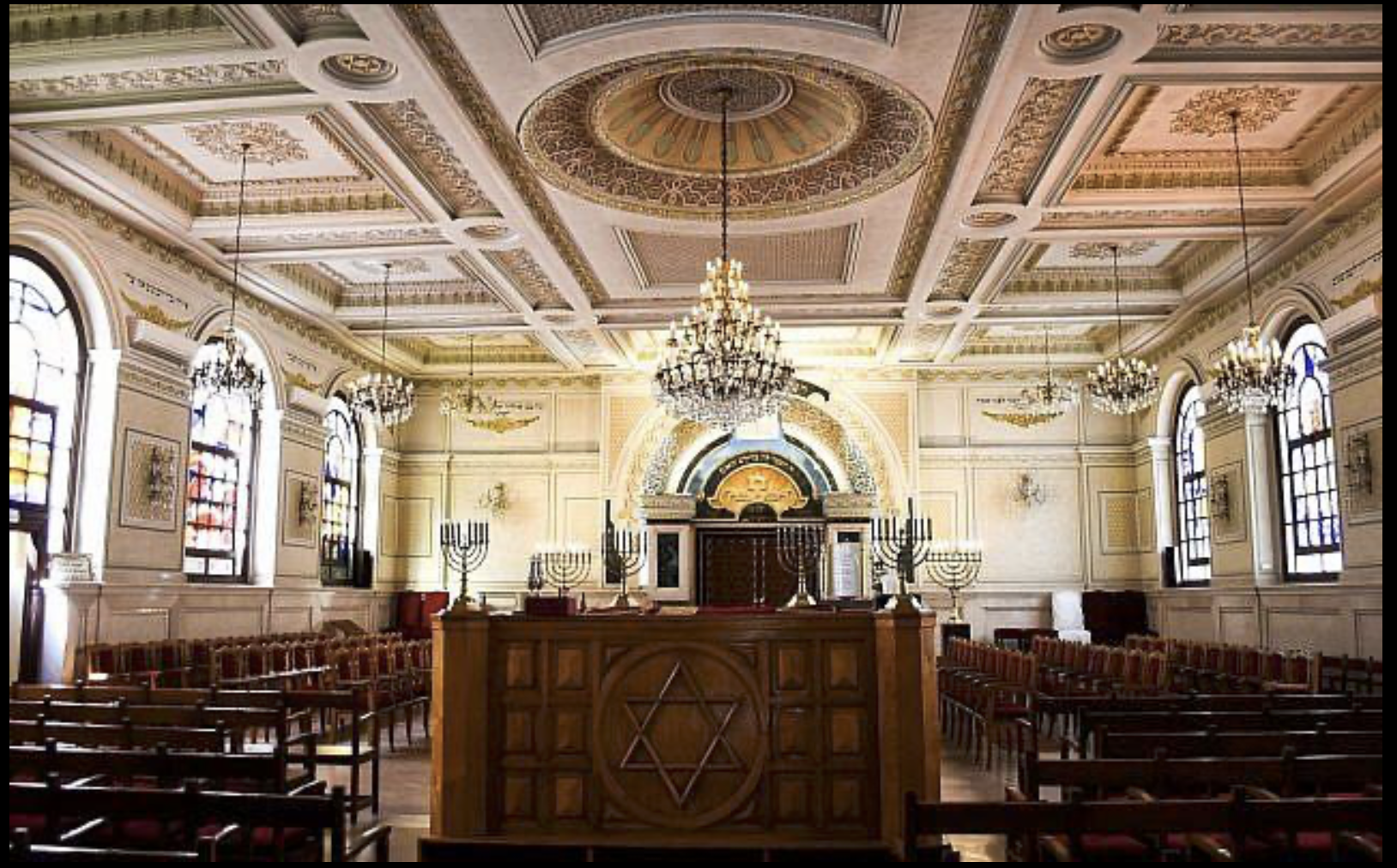 Historic synagogue interior in Morocco — carved plasterwork, arched windows and zellige tilework